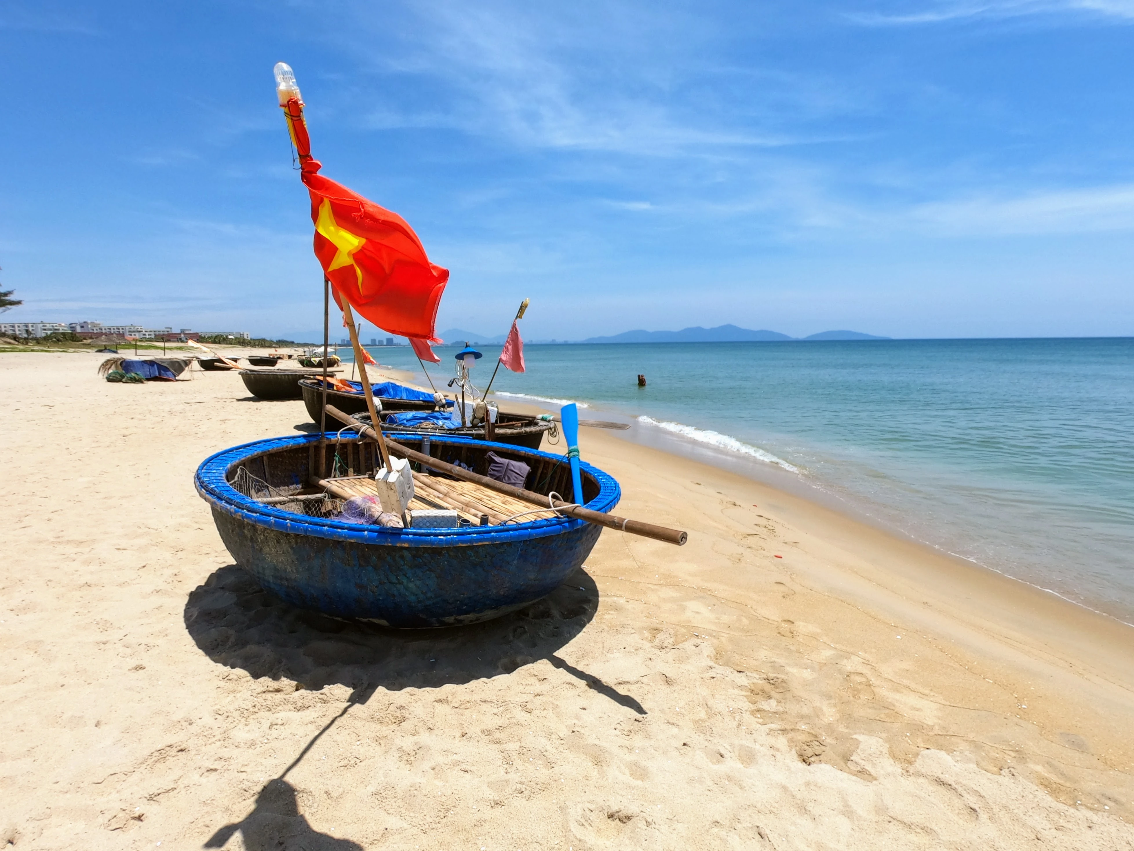 Traditional Vietnamese basket boats on An Bang Beach, Vietnam with red flag flying and turquoise waters