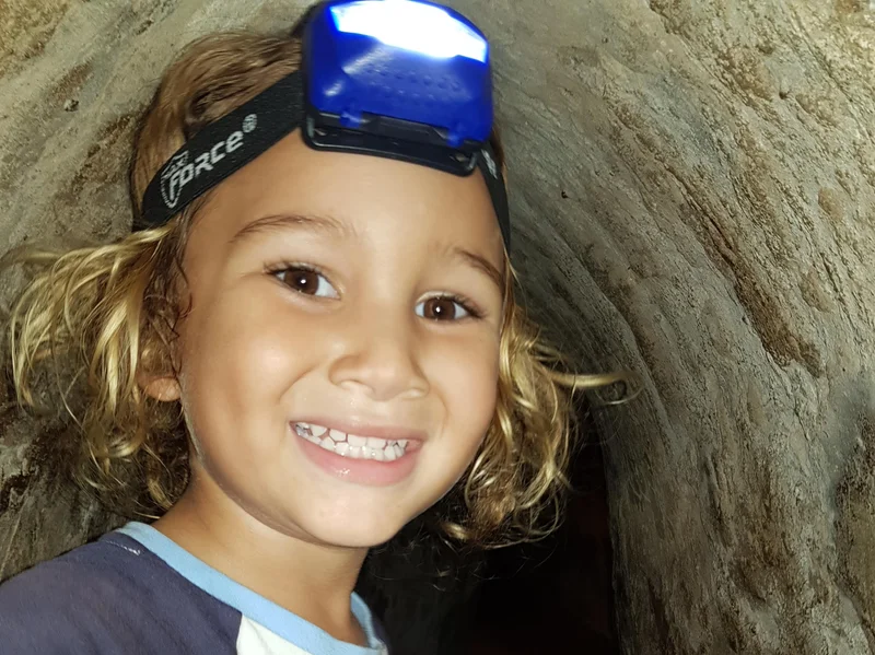 Elijah smiling brightly while wearing a headlamp inside the Cu Chi Tunnels, showing his excitement for the adventure