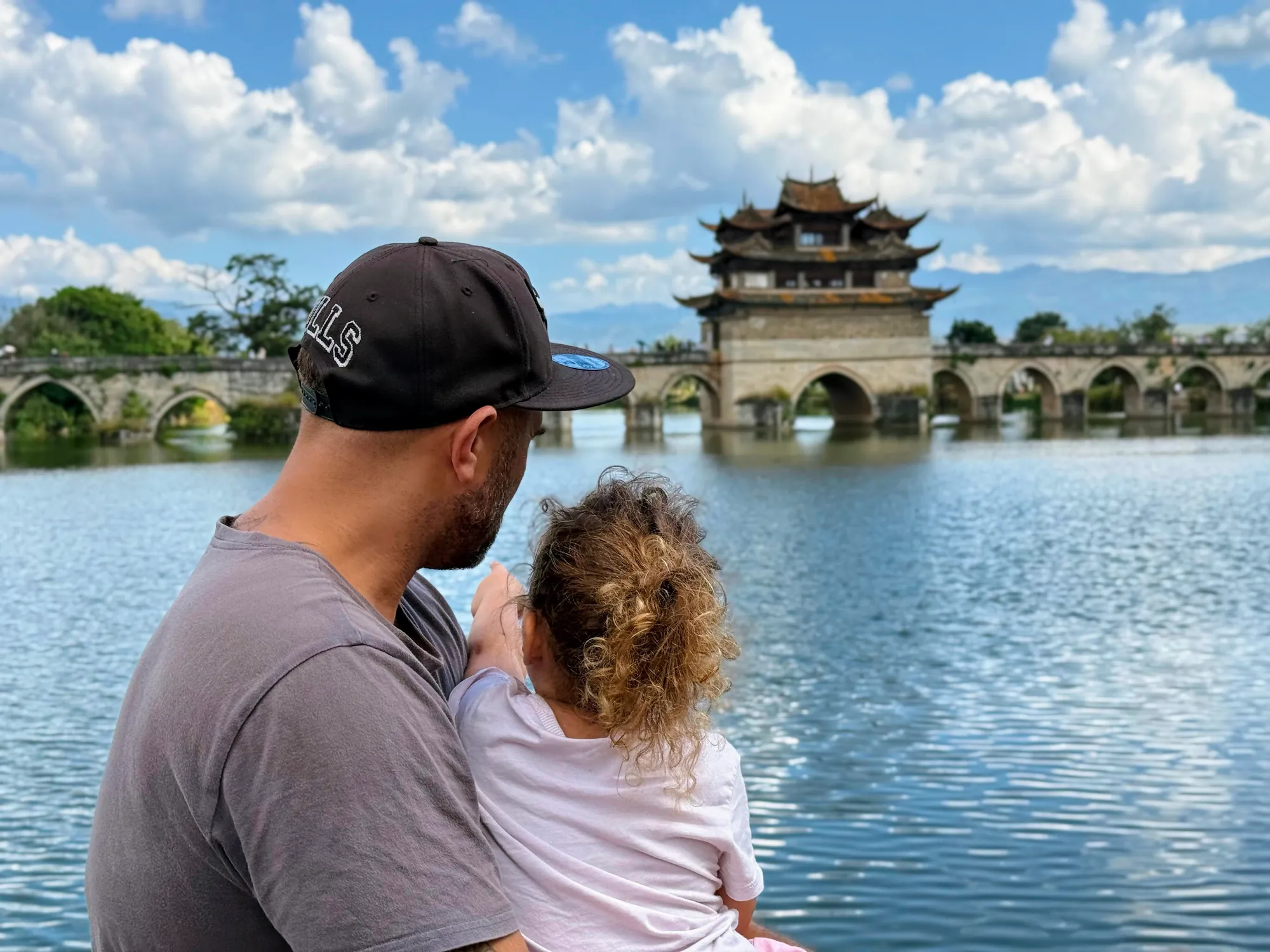 Father and daughter enjoying the ancient Double Dragon Bridge in Jianshui, China