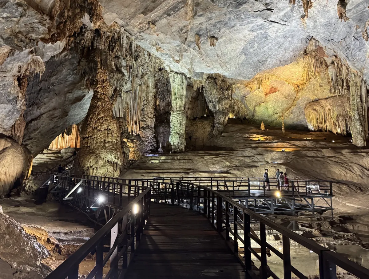Paradise Cave Phong Nha Vietnam - Majestic cave interior with wooden boardwalk and stunning limestone formations illuminated by artificial lights - World Travel Ambitions