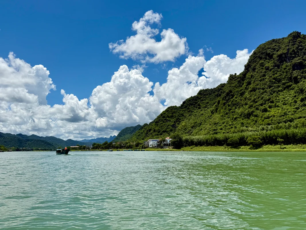Phong Nha Cave Boat Vietnam - Traditional boat on turquoise river surrounded by lush green mountains and blue sky - World Travel Ambitions