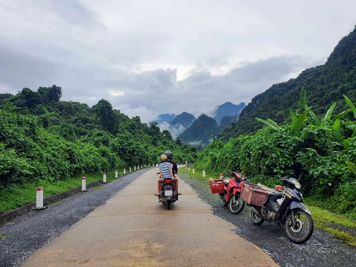 Phong Nha Loop Vietnam - Scenic mountain road winding through lush jungle with limestone karsts and misty clouds - World Travel Ambitions