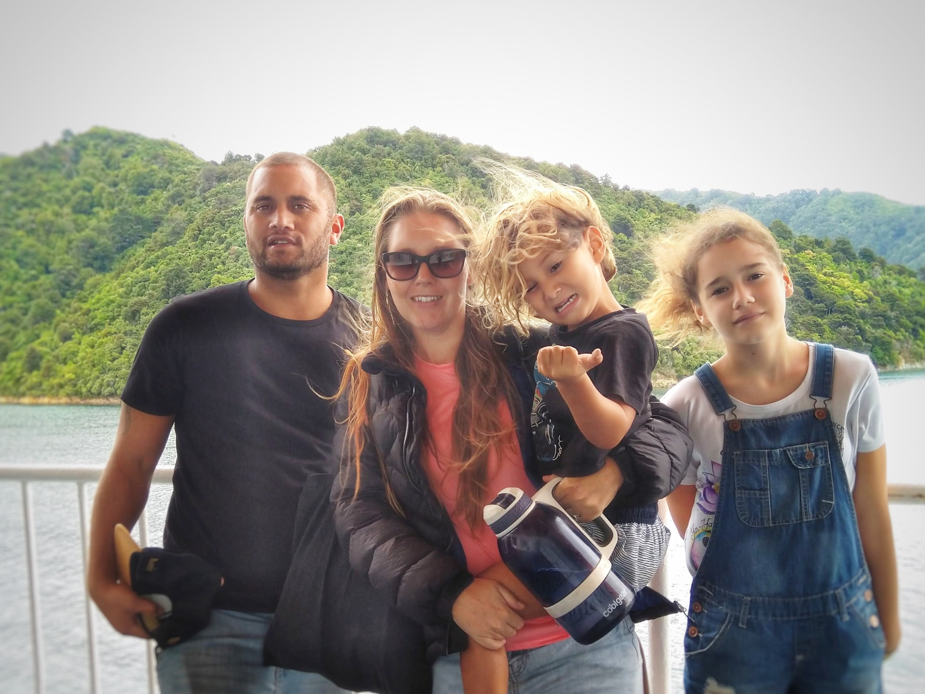 Family of four on Interislander ferry from Picton to Wellington with beautiful mountain backdrop in New Zealand