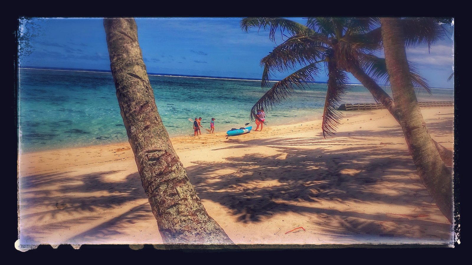 Kayaks and palm trees at Vaimaanga Beach, Rarotonga