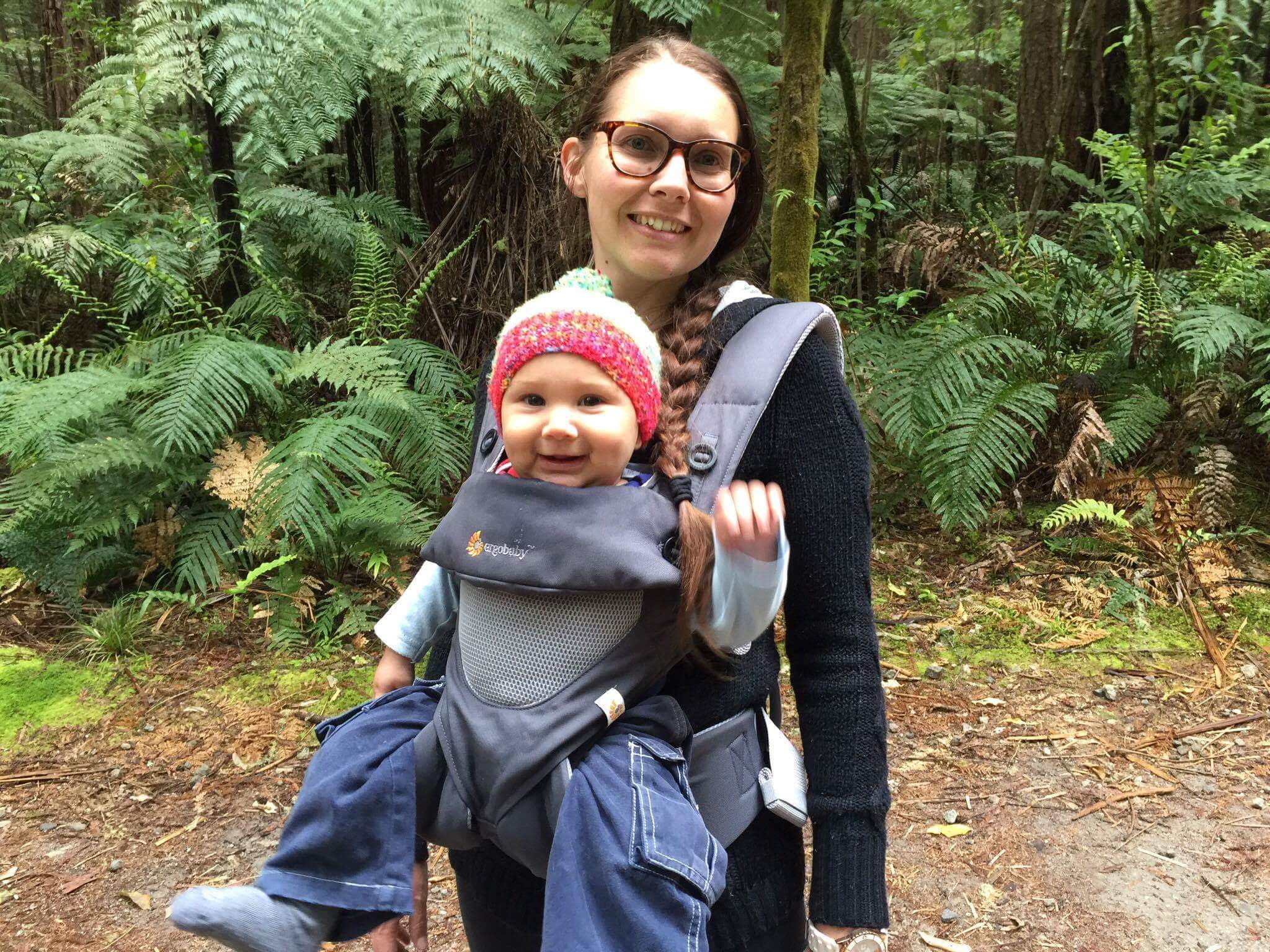 Family enjoying a walk in Rotorua's Redwood Forest with baby in carrier among towering trees and lush ferns