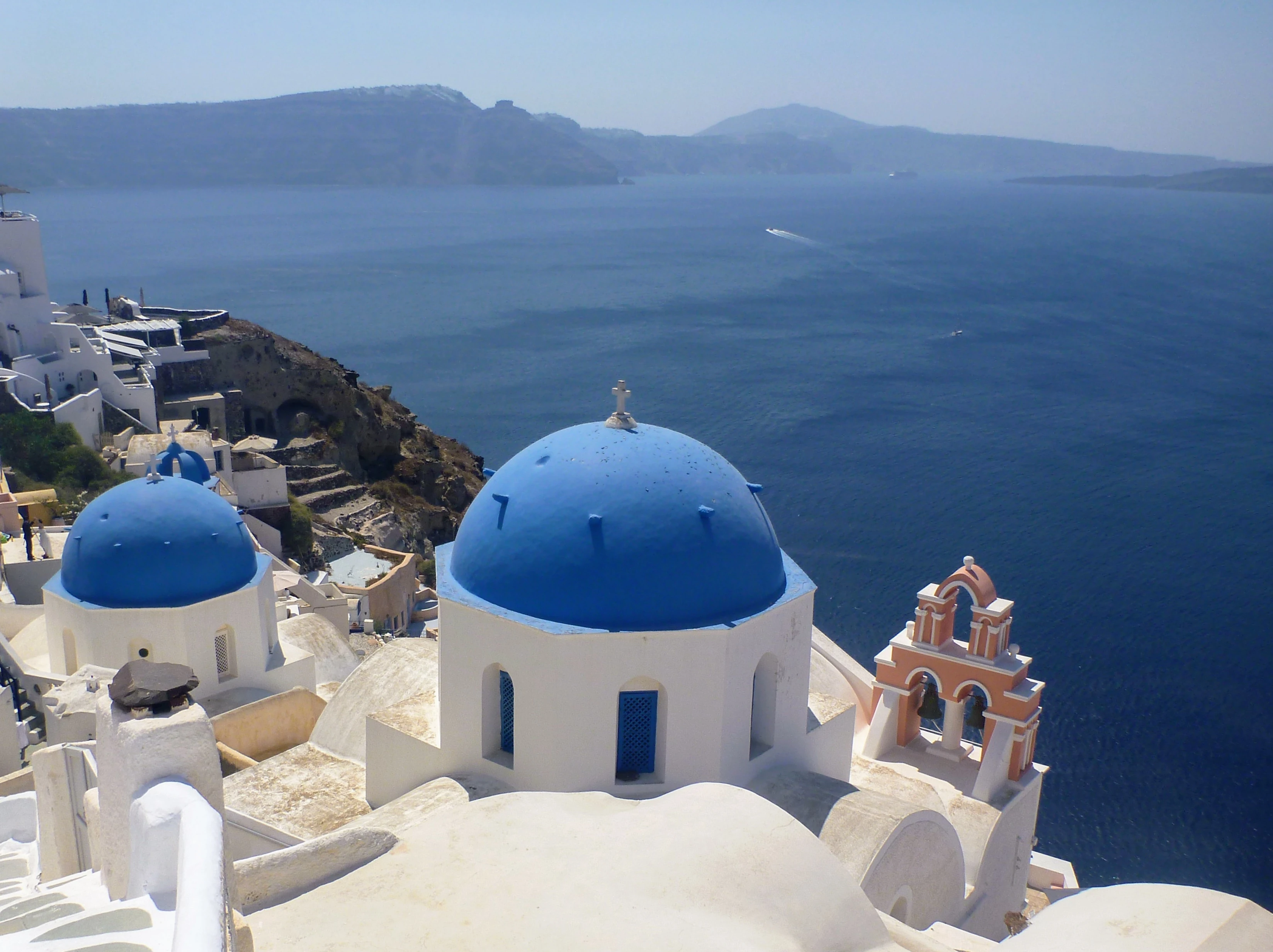 Stunning panoramic view of Santorini, Greece with iconic white-washed buildings and vibrant blue domes overlooking the deep blue Aegean Sea