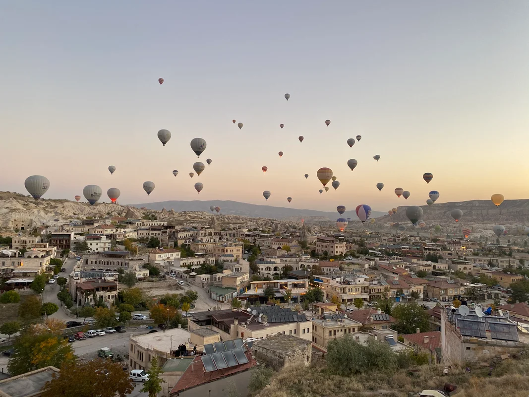 Hot air balloons over Cappadocia, Turkey - A breathtaking sunrise scene with dozens of colorful balloons floating above ancient rock formations
