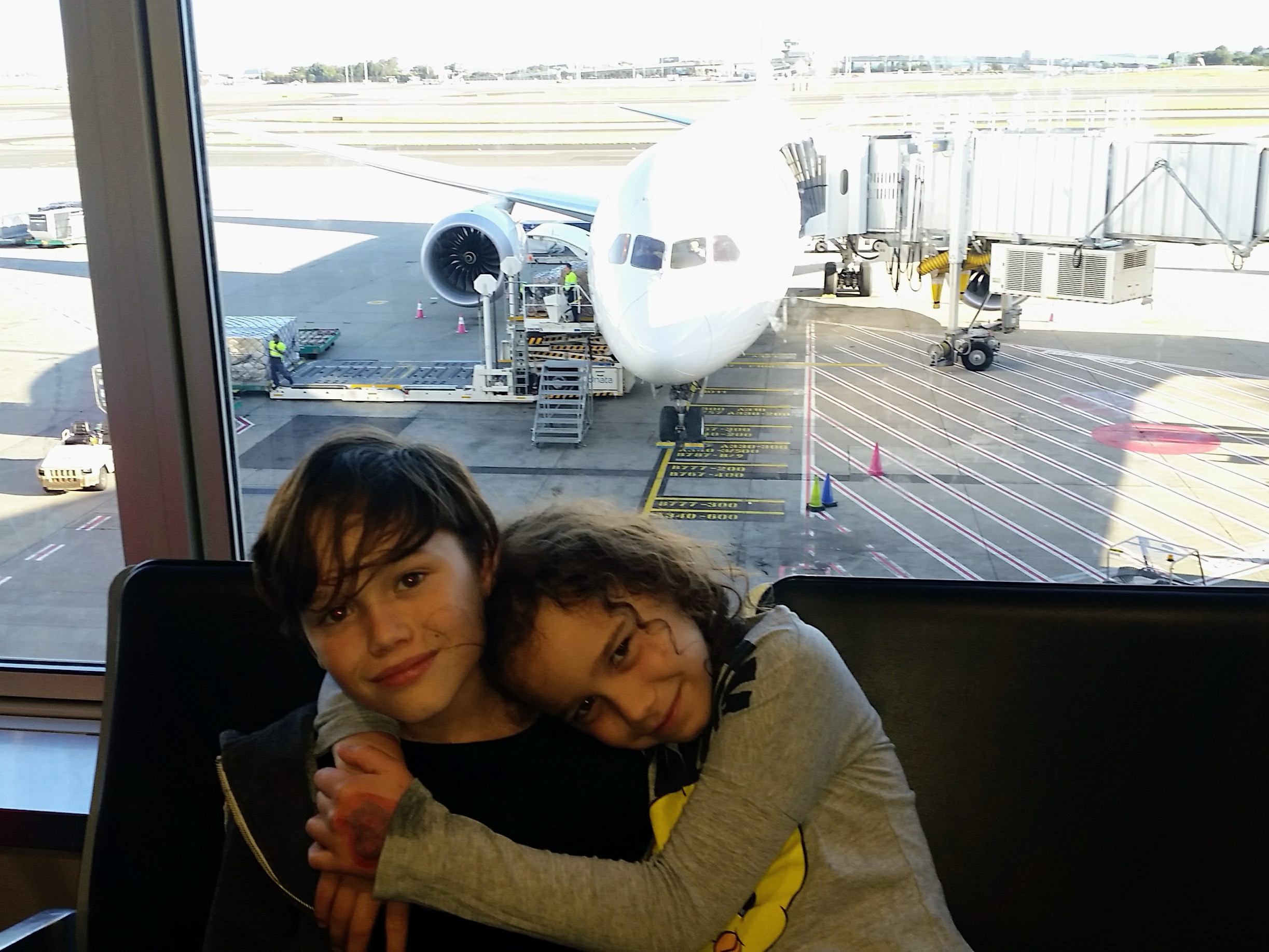 Noah and Aaliyah waiting at the airport gate before their worldschooling adventure to New Zealand
